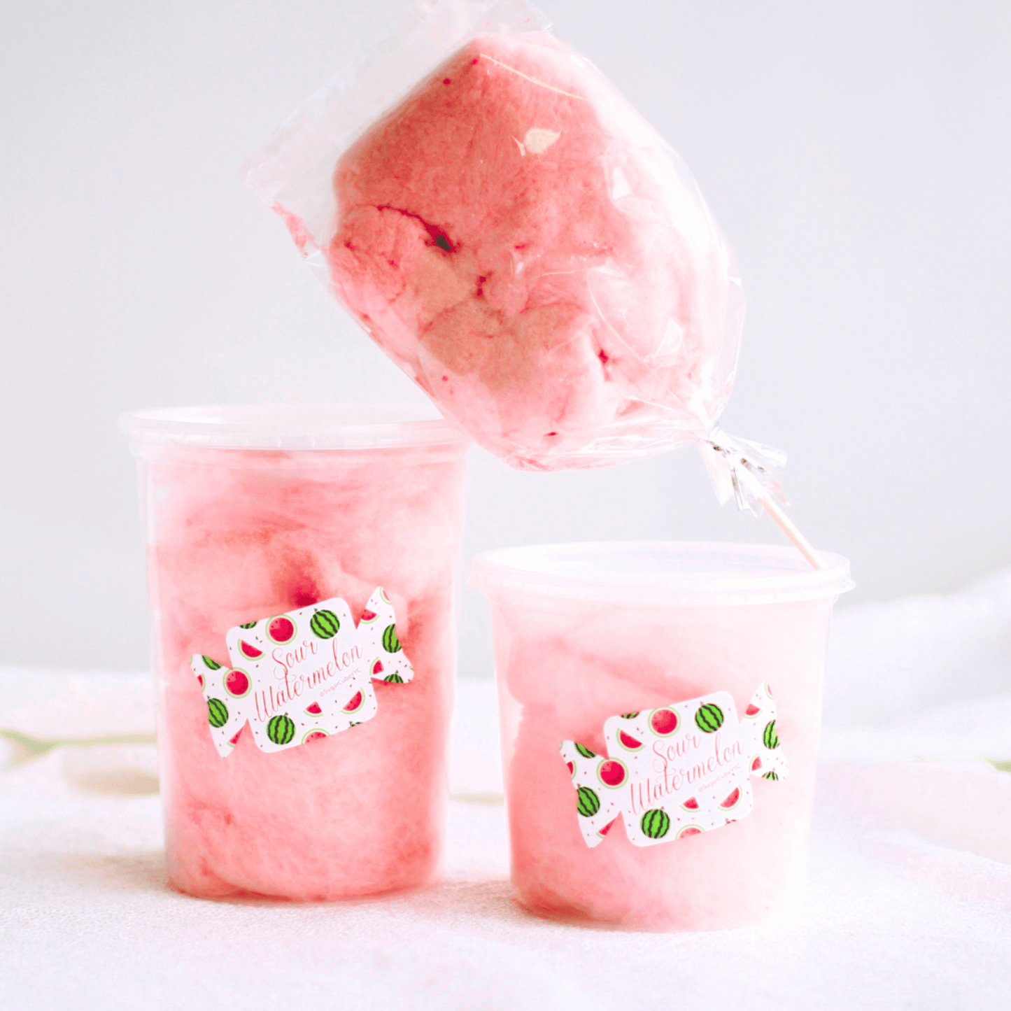 Fresh pink cotton candy packaged in sealed tubs and a bag to help maintain freshness.