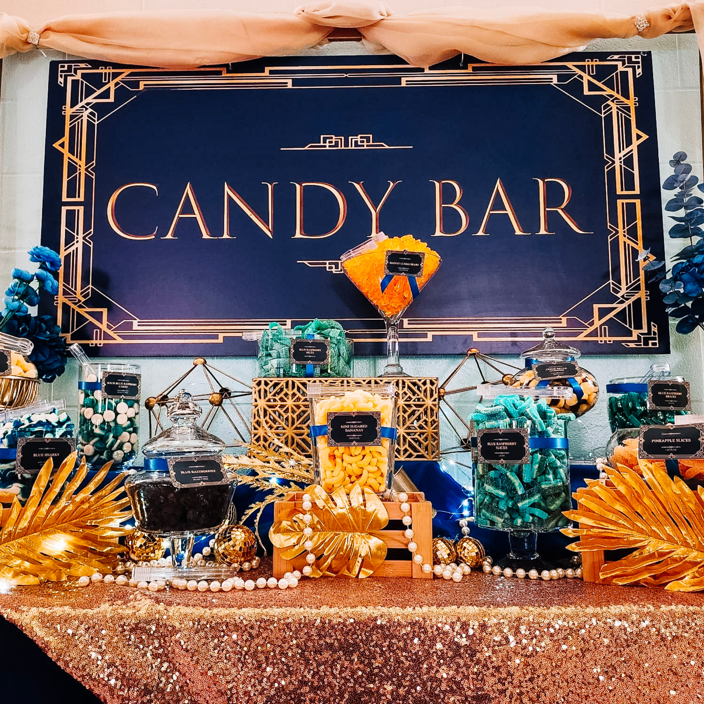 Professionally styled blue and gold candy buffet with custom backdrop, decor and premium candy