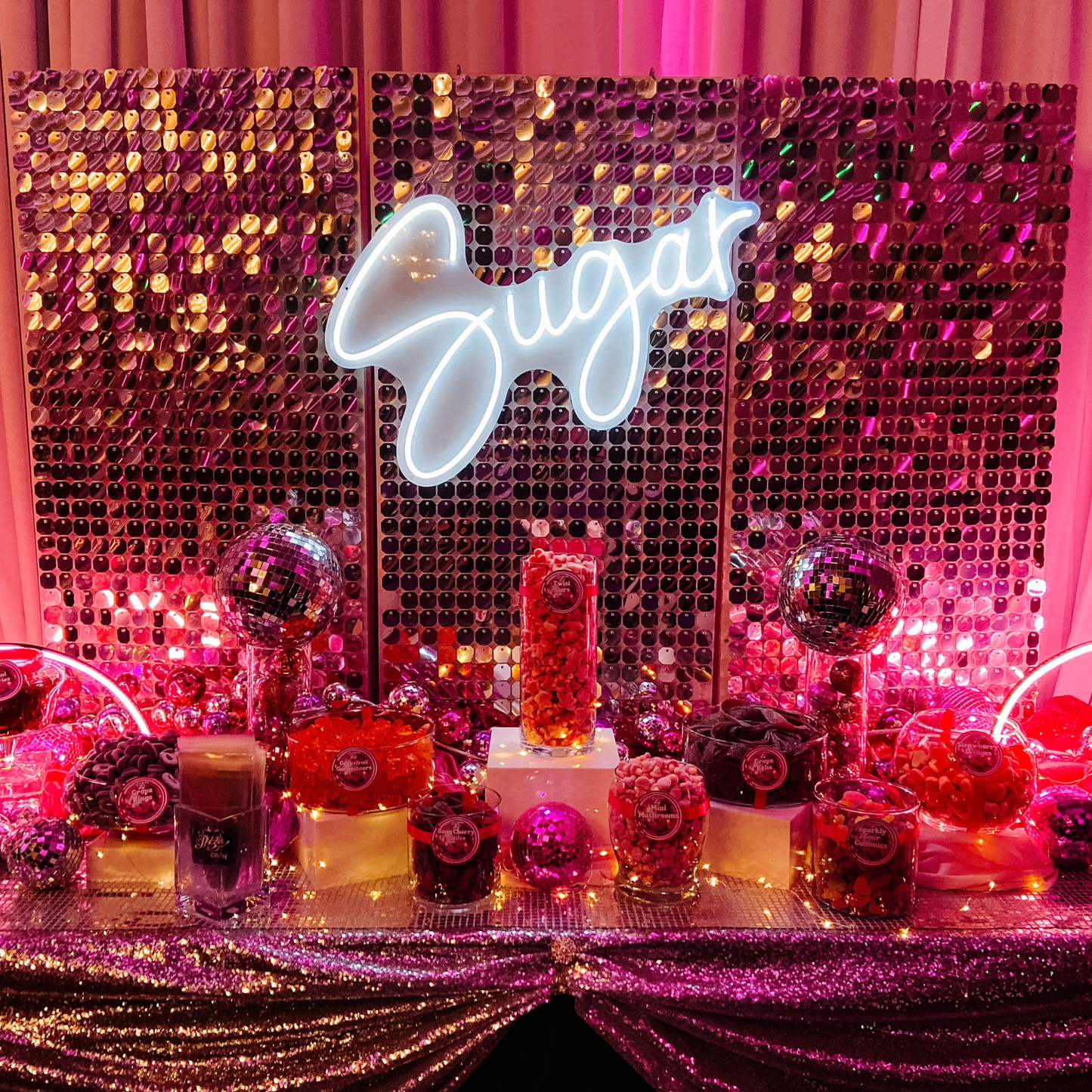Professionally styled candy buffet with colourful candy, sequin backdrop, disco balls and custom event decor