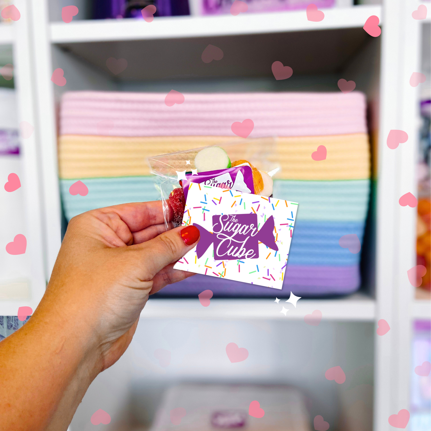The Sugar Cube digital candy gift card shown in hand with colourful candy products in the background