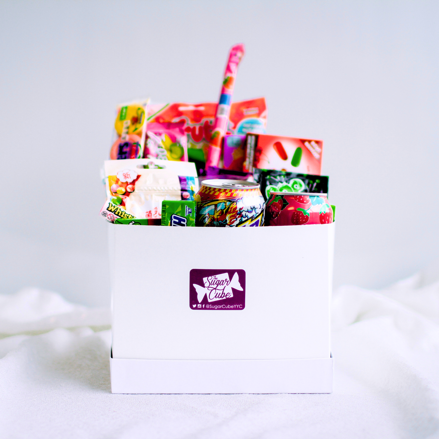 Large candy gift basket with approximately 15 to 20 assorted treats, including specialty soda bottles and cans
